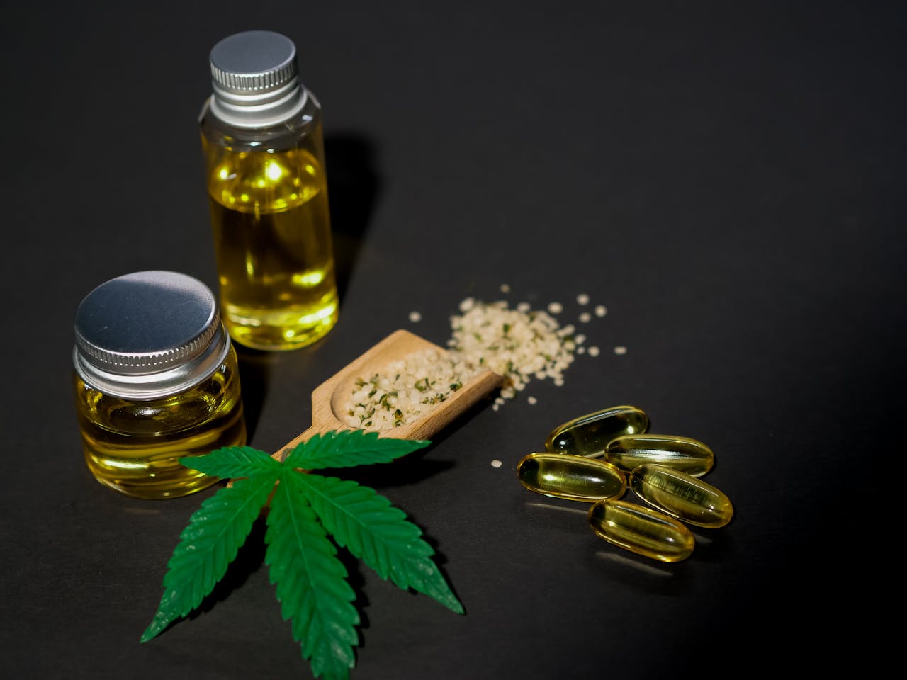 Services High-quality image featuring cannabis oil, seeds, leaves, and capsules on a dark background.