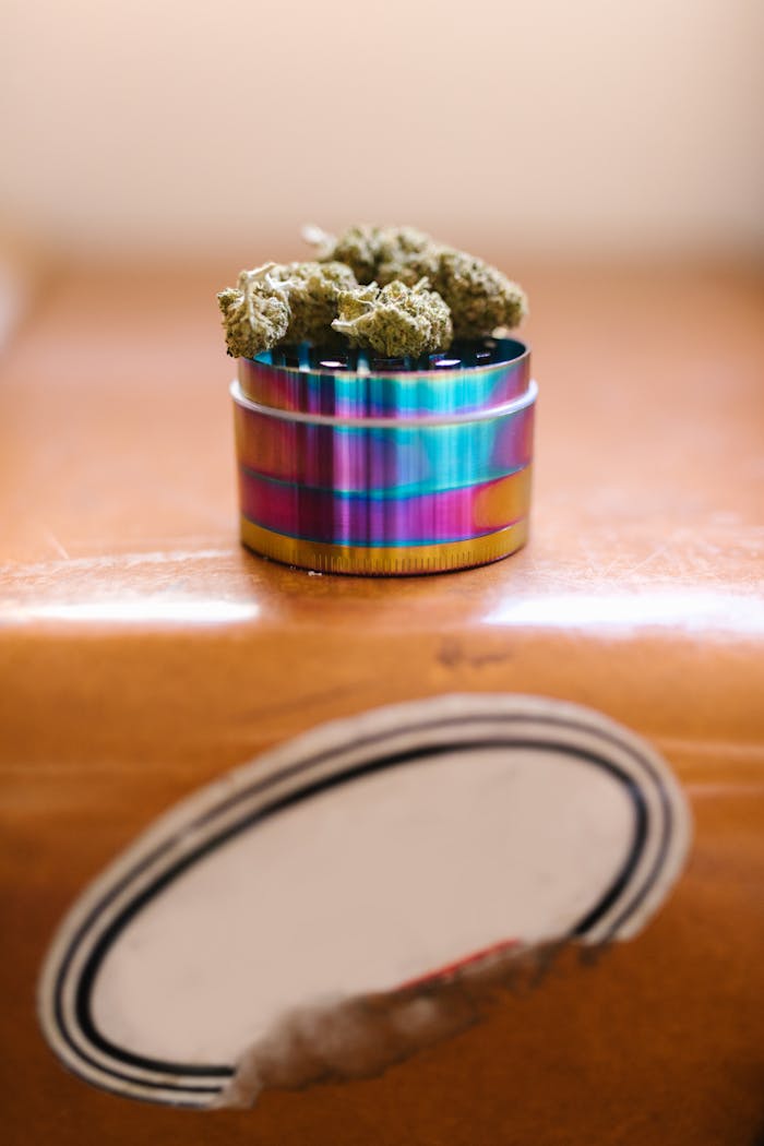 Services Colorful weed grinder with cannabis buds, shot from above with soft lighting and selective focus.